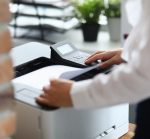 Woman In Office Prints Documents On Printer. Scanning Documents At Workplace Concept